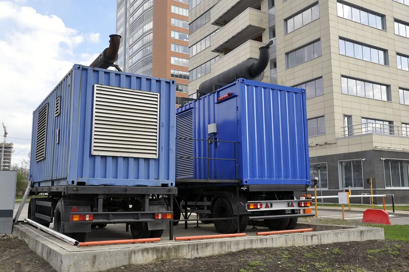 Containerized industrial diesel generators beside a building