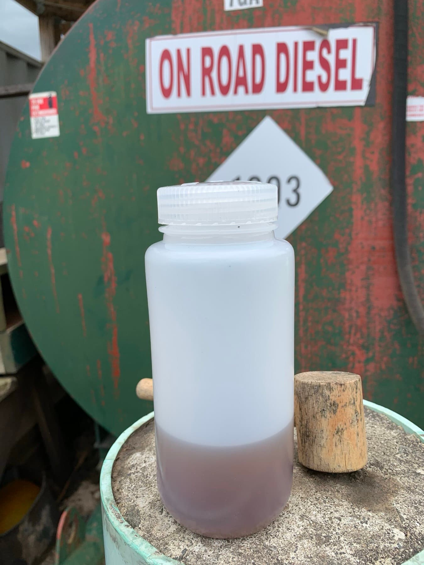 Diesel sample drawn from an on-road diesel tank, showing haze and sediment consistent with water contamination